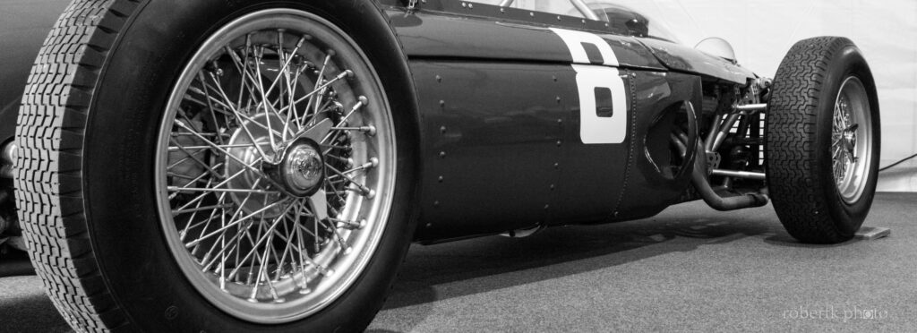 Monochrome close-up of a vintage racing car wheel and fender