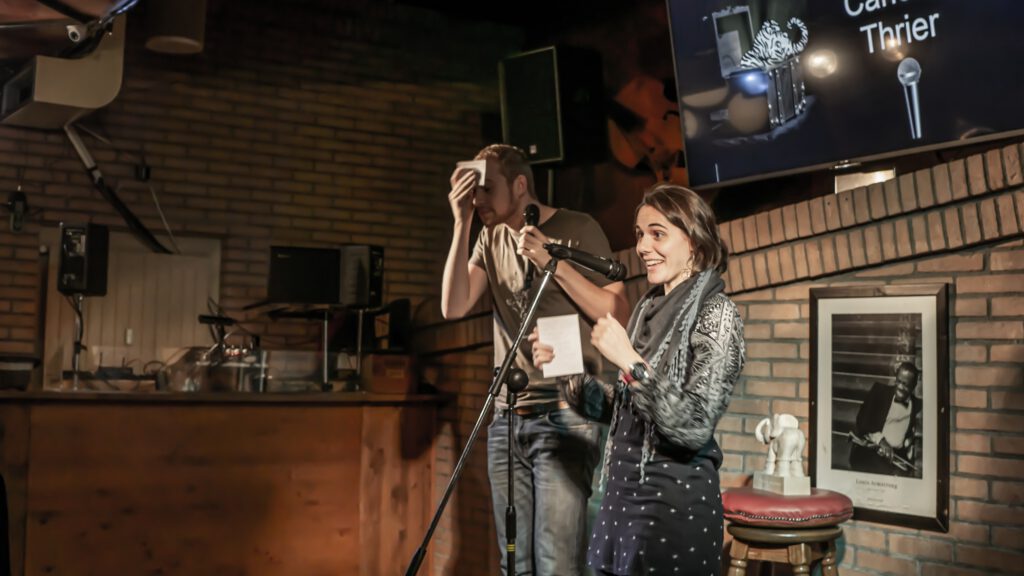 Two performers standing together at the Poetry Slam microphone