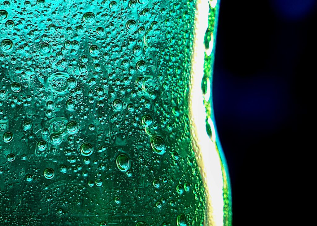 Close-up of a green glass bottle covered in water droplets