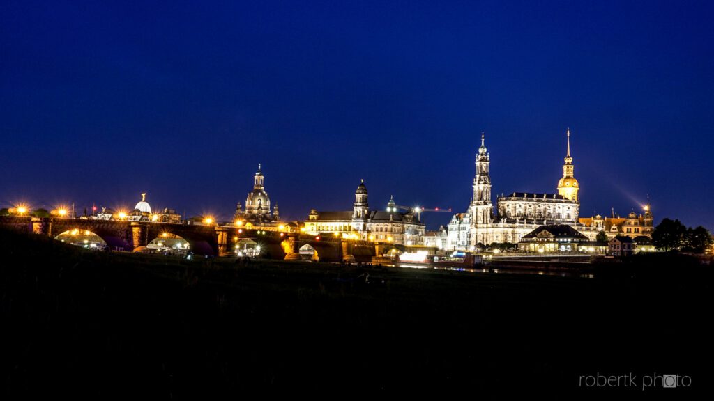 Dresden skyline glowing at night beside the dark river