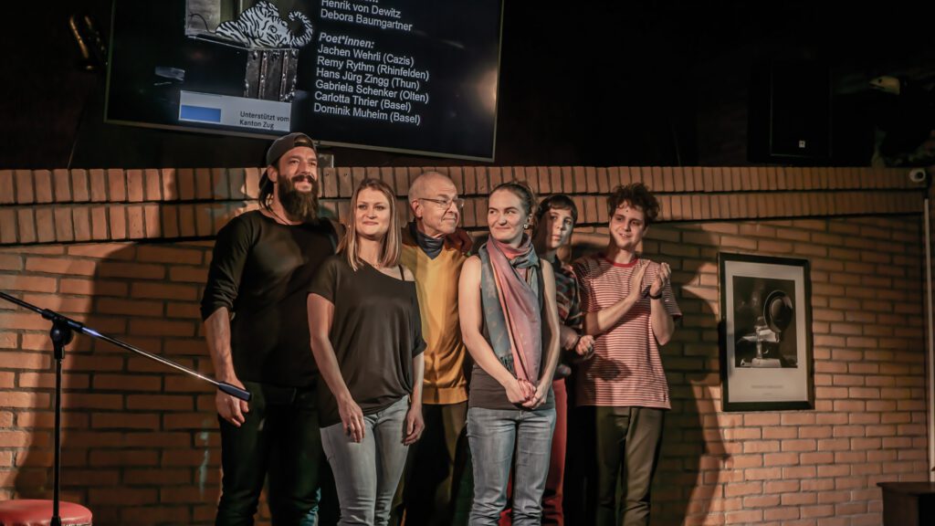 Group of six Poetry Slam performers standing together on stage