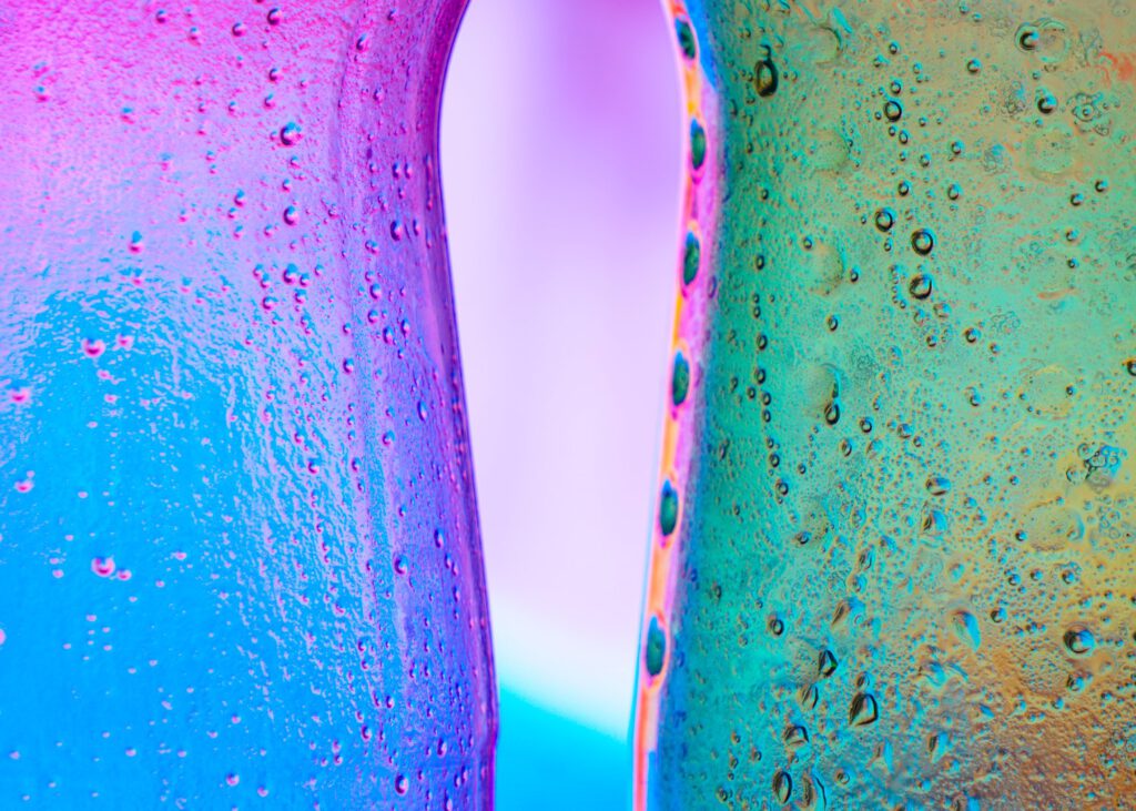 Blue, pink, and green glass bottles meeting in a colorful close-up
