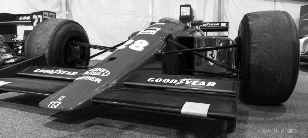 Monochrome view of a vintage racing car in an exhibition hall