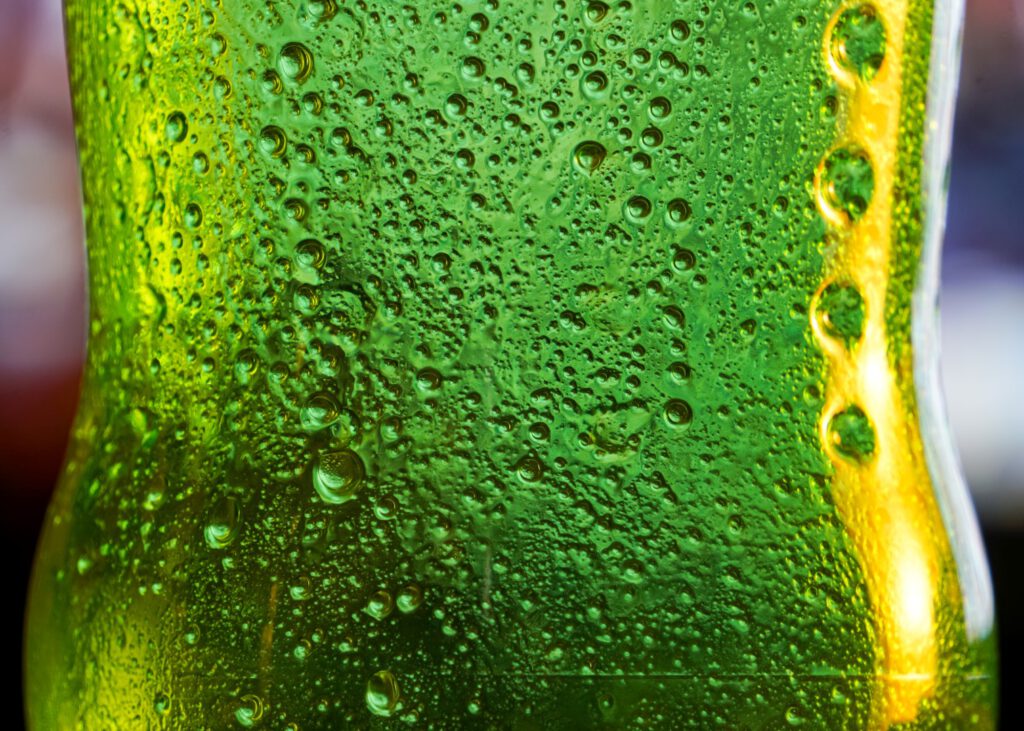 Close-up of a lime green glass bottle covered with condensation