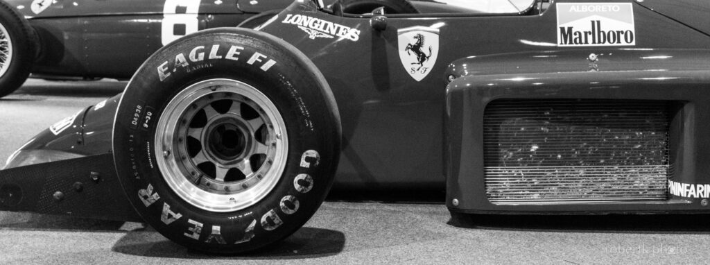 Monochrome close-up of a classic race car body and rear wheel