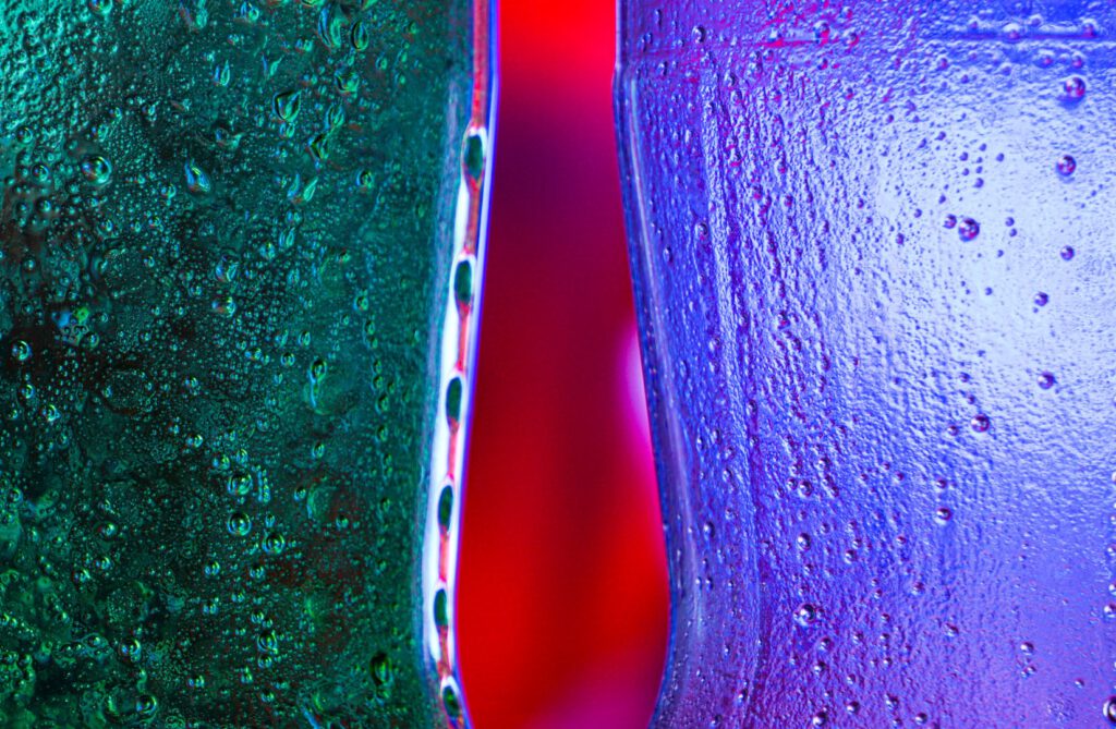 Close-up of dark teal and purple glass bottles against red light