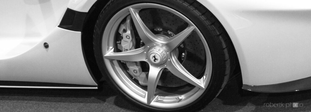 Monochrome close-up of a Ferrari sports car wheel